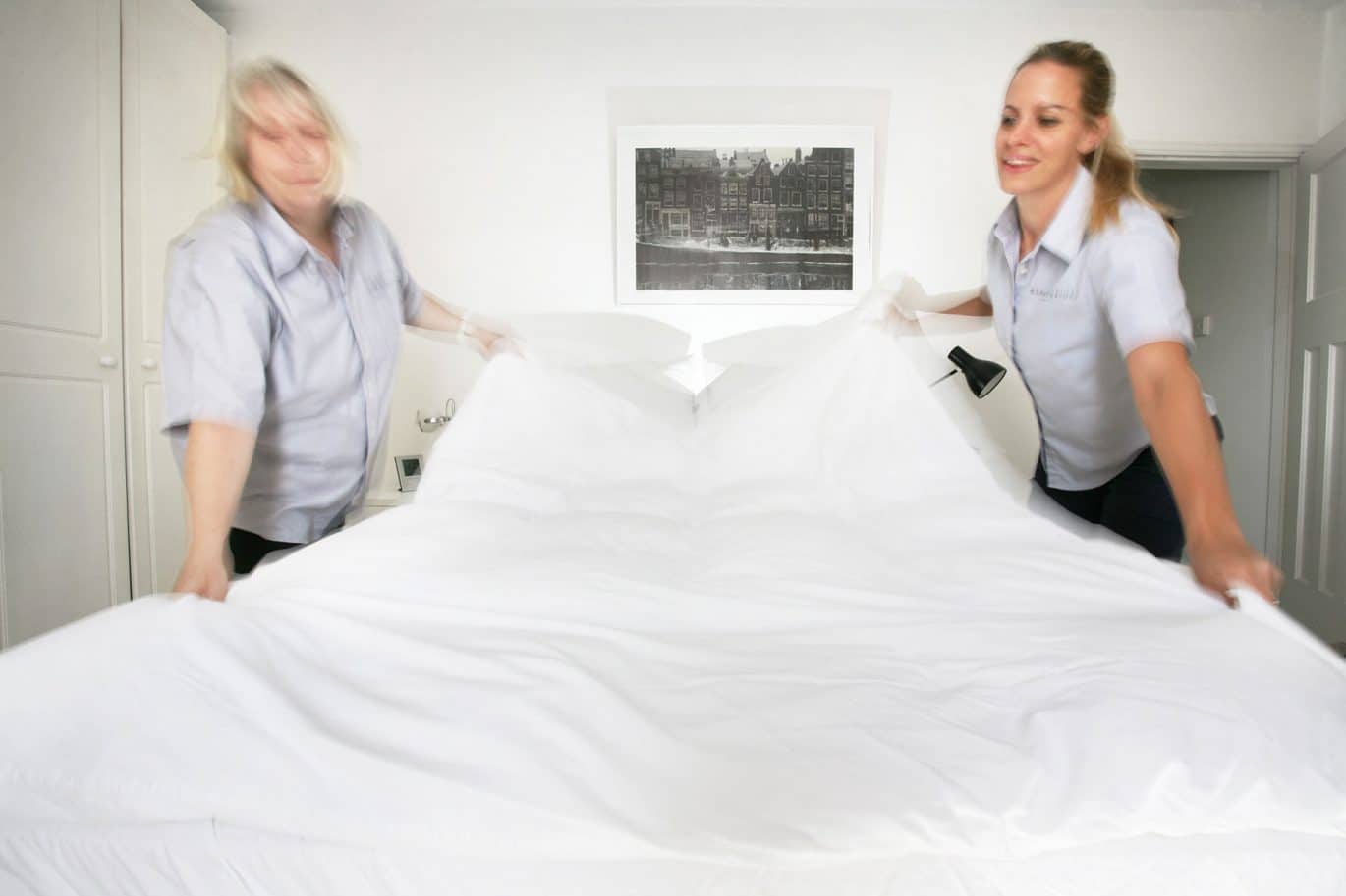 Two domestic cleaners making a bed